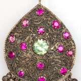 Buddhistischer Amulett-Anhänger, Metall mit 14 Rubinen von je ca. 1 ct. und Kiwi-Topas besetzt, tropfenförmiger Anhänger rücks. mit Buddha-Relief, beweglich anhängende Kugel (1x fehlt), L. mit Öse L. 9 cm - фото 1