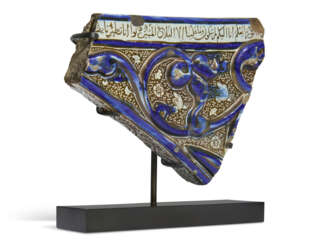 A KASHAN MOULDED LUSTRE AND COBALT-BLUE POTTERY TILE SPANDREL FRAGMENT