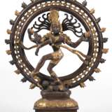Skulptur "Shiva Nataraja, die auf einem Dämon tanzende hinduistische Gottheit", Bronze, dunkel patiniert und golfarbend gefasst, auf getrepptem Sockel, H. 35,5 cm - photo 1