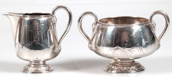 Zuckerschale und Sahnekännchen, Silber, Kopenhagen 1877, Meister Emil F. Dahl, je auf reliefiertem Rundfuß, Wandungen mit Engeldarstellungen, hochgezogene Henkel mit reliefierten Ansätzen, unterseitig monogr. und dat. 19… - photo 1
