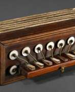 Instruments and tools. Kinder Ziehharmonika mit Holzeinlagen sowie Perlmutt- Messinghebeln, Blasebalk mit bedrucktem Papier beklebt um 1900, 9,6x23,5x8,8cm, bespielt, 1 Perlmutttaste fehlt