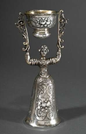 Historismus Hochzeitsbecher in Form einer stehenden Frau ein Gefäß hochhaltend, Kleid und Becherwandung mit Frucht- und Blütendekor sowie rückseitiger Groteske, MZ: Neresheimer, Hanau, letztes Viertel 19.Jh., Silber inne… - Foto 1