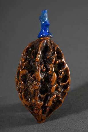 Geschnitzter Kern als Snuffbottle gearbeitet mit kleinen Personendarstellungen auf Erhebungen mit länglichem blauem Steinstöpsel, L. 6cm - photo 1