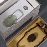 Feine sehr dünnwandige Hotan Jade Deckelvase in Hu-Form mit Flachrelief "Phönixe und Taotie Masken" in archaischem Stil mit beweglichem Bügel und Ringen, in Holzsockel und Präsentoir, dazu Brokat bezogener Kas… - photo 8