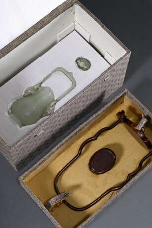 Feine sehr dünnwandige Hotan Jade Deckelvase in Hu-Form mit Flachrelief "Phönixe und Taotie Masken" in archaischem Stil mit beweglichem Bügel und Ringen, in Holzsockel und Präsentoir, dazu Brokat bezogener Kas… - photo 8