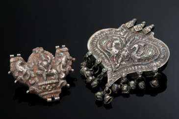 2 Diverse indische Amulette mit getriebenen Darstellungen und Resten roter Fassung: herzförmiger zu öffnender Behälter mit 2 Vögeln und Schellenbehang (11,8x9,2cm) und &quot;Widderkopf&quot; mit Ganesha und 2 Tieren (6,6…