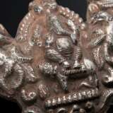 2 Diverse indische Amulette mit getriebenen Darstellungen und Resten roter Fassung: herzförmiger zu öffnender Behälter mit 2 Vögeln und Schellenbehang (11,8x9,2cm) und "Widderkopf" mit Ganesha und 2 Tieren (6,6… - photo 4