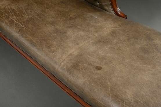 Englische Mahagoni Chaiselongue mit kapitoniertem olivgrünem Lederpolster auf geschnitztem Mahagoni Gestell mit plastischem Delphin sowie floraler Schnitzerei auf 4 Säulenfüßen, 1. Hälfte 19.Jh., 43/90x197x66cm, schöne P… - photo 3