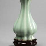 Seladonfarben glasierte Vase in passig gerippter Form auf Holzstand - Foto 1