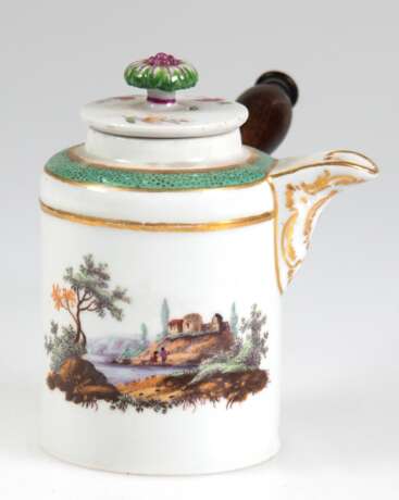 Schokoladenkännchen, 18./19. Jh., undeutl. kl. Blaumarke, zylindrischer Korpus mit seitl. montierter Holzhandhabe, beidseitig feine polychrome Landschaftsmalerei, Goldränder, Deckel mit Blumenbemalung und plastischer Blü… - photo 1