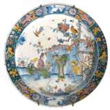 Fayence Platte, Delft, 1. Hälfte 18. Jh., polychromer Scharffeuerdekor im ostasitischen Stil, figürliche Darstellung mit hohen Frisuren, polychromer Rand mit Blumen und Vögeln, Rand und Rückseite mit Glasurfehlstellen, H… - photo 1
