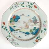 Großer China-Teller, achteckig, Periode Chien-Lung (1736-1795), leicht blaugraue Glasur bemalt mit polychromen Emailfarben famille rose, im Spiegel Darstellung einer chinesischen Landschaft, Fahne mit Blumenranken, dazwi… - Foto 1