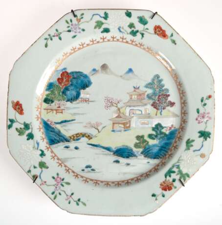 Großer China-Teller, achteckig, Periode Chien-Lung (1736-1795), leicht blaugraue Glasur bemalt mit polychromen Emailfarben famille rose, im Spiegel Darstellung einer chinesischen Landschaft, Fahne mit Blumenranken, dazwi… - Foto 1