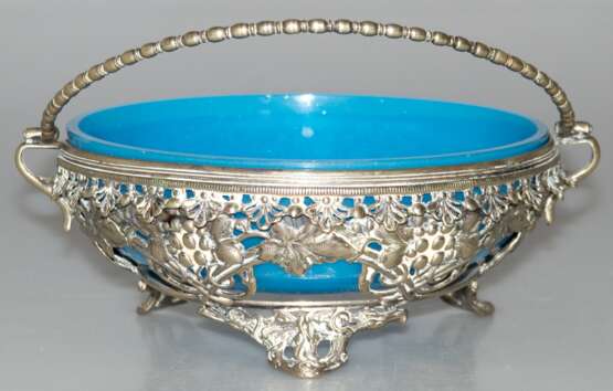 Henkelschale mit blauem Glaseinsatz, um 1900, durchbrochene silberfarbene Metallwandung mit Weinlaubdekor, Glasschale mit kl. Randchip, H. (ohne Henkel gemessen) 8 cm, Dm. 18 cm - photo 1