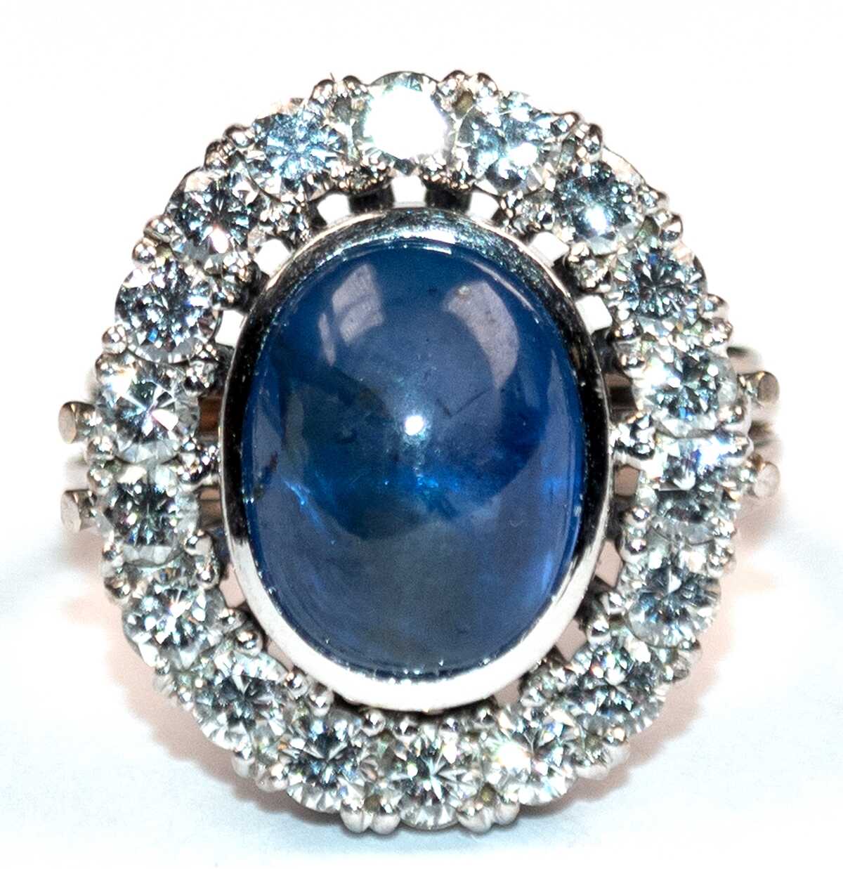 Saphir-Brillant-Ring, 585er WG, ausgefaßt mit 1 ovalen Saphir-Cabochon von ca. 7,15 ct., helles Blau und 18 Brillanten von zus. ca. 1,08 ct., LR - VVS, Ges.-Gew. 8,44 g, RG 49(Wiederbeschaffungswert lt. Expertise 4.190,-…