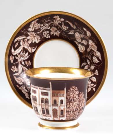 KPM-Tasse mit UT, datiert "Johann Chutholt 1857", mit architektonischer Darstellung und Floraldekor in Braun, Goldränder, UT mit Floraldekor auf braunem Grund, Goldränder, blaue Zeptermarke, Tasse zusätzl. mi… - photo 1
