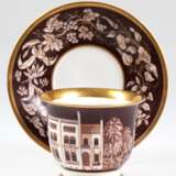 KPM-Tasse mit UT, datiert "Johann Chutholt 1857", mit architektonischer Darstellung und Floraldekor in Braun, Goldränder, UT mit Floraldekor auf braunem Grund, Goldränder, blaue Zeptermarke, Tasse zusätzl. mi… - photo 1