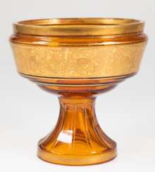Art-Deco-Fußschale, Moser, bernsteinfarbenes Glas mit Goldbemalung, Schale mit goldener Reliefbordüre mit Wein- und Vogeldekor, Gold partiell berieben, H. 19 cm, Dm. 19 cm