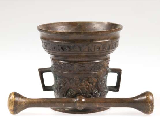 Mörser mit Pistill, Altbeschriftung, Bronze, umlaufend ornamental reliefiert, 2 gekantete Henkel, H. 8,5 cm, Pistill-L. 15 cm - photo 1
