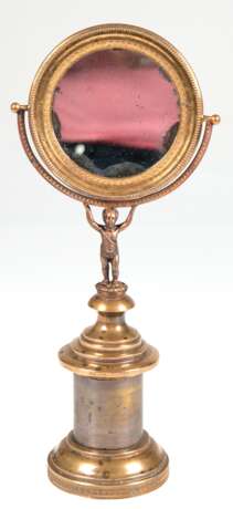 Schminkspiegel, figürlich, Bronze, Frankreich 19. Jh., auf beschwertem, getrepptem Rundfuß steht plastischer Putto und trägt schwenkbaren Spiegel (mit Blindstellen), Ges.-H. 30 cm, Spiegel-Dm. 11 cm - Foto 1