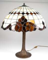 Tischlampe im Tiffany-Stil, 1-flammig, Bronzefuß in Form eines Baumstammes, runder Schirm aus beige/braunem Kunstglas, H. 60 cm, Dm. 56 cm
