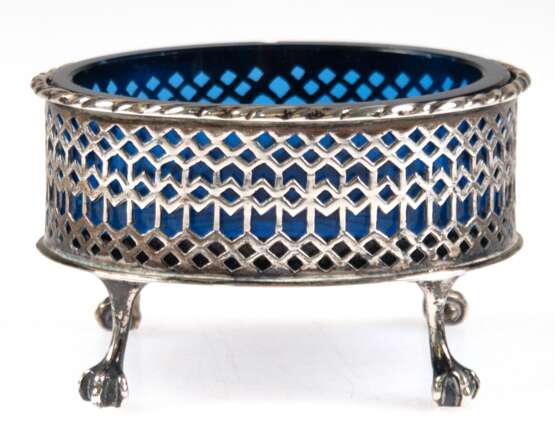 Saliere mit blauem Glaseinsatz, 19. Jh., Silber (geprüft), oval, auf 4 Tatzenfüßen, durchbrochene Wandung mit Kordelrand, Glaseinsatz mit Sternschliff (Rand min. best.), Gew. (ohne Glas) 54,3 g, 5x8x6,5 cm - Foto 1