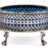 Saliere mit blauem Glaseinsatz, 19. Jh., Silber (geprüft), oval, auf 4 Tatzenfüßen, durchbrochene Wandung mit Kordelrand, Glaseinsatz mit Sternschliff (Rand min. best.), Gew. (ohne Glas) 54,3 g, 5x8x6,5 cm - Foto 1