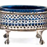 Saliere mit blauem Glaseinsatz, 19. Jh., Silber (geprüft), oval, auf 4 Tatzenfüßen, durchbrochene Wandung mit Kordelrand, Glaseinsatz mit Sternschliff (Rand min. best.), Gew. (ohne Glas) 54,3 g, 5x8x6,5 cm - Foto 1