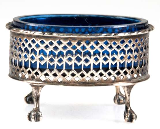 Saliere mit blauem Glaseinsatz, 19. Jh., Silber (geprüft), oval, auf 4 Tatzenfüßen, durchbrochene Wandung mit Kordelrand, Glaseinsatz mit Sternschliff (Rand min. best.), Gew. (ohne Glas) 54,3 g, 5x8x6,5 cm - Foto 1