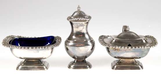 3 Gewürzbehälter, versilbert, um 1900, dabei Saliere mit blauem Glaseinsatz, Senfgefäß mit blauem Glaseinsatz und Salzstreuer, jeweils mit Kordelrand und Muscheldekor, Gebrauchspuren, H. 5 cm bis 11,5 cm - Foto 1