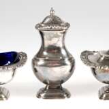 3 Gewürzbehälter, versilbert, um 1900, dabei Saliere mit blauem Glaseinsatz, Senfgefäß mit blauem Glaseinsatz und Salzstreuer, jeweils mit Kordelrand und Muscheldekor, Gebrauchspuren, H. 5 cm bis 11,5 cm - Foto 1