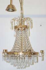 Deckenleuchter mit reichem Kristallbehang, an reliefiertem Metallreif 5 Kerzenhalter und innen 3 Glühlampen, H. ca. 85 cm, Dm. 46 cm