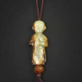 A RARE PALE YELLOW AND RUSSET JADE CARVING OF A BOY HOLDING A BIRD - photo 1