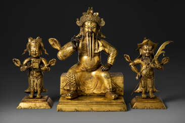 A GILT-COPPER REPOUSS&#201; FIGURE OF GUANDI AND TWO ATTENDANTS