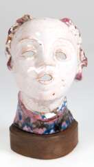 Maskenartiger Keramikkopf, 1920er Jahre, farbig glasiert, undeutlich signiert und Ränder beschädigt, auf Holzplinthe, Ges.-H. 21 cm
