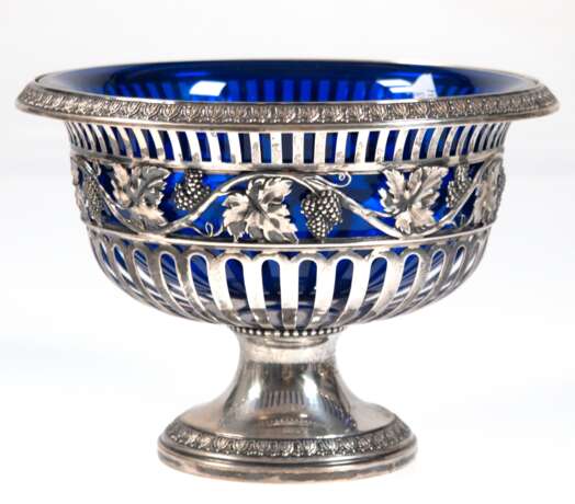Fußschale mit blauem Glaseinsatz, 800er Silber, Wilkens, durchbrochene Schale mit Traubendekor auf Rundfuß, Ränder mit Palmettenrelief, Gew. (ohne Glaseinsatz) 478 g, H. 15,5 cm, Dm. 20,5 cm - photo 1