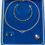 Rubin-Brillant-Schmuckset, 750er GG/WG, 5-teilig, bestehend aus Collier, Armband, Ring und Paar Ohrsteckern, Collier mit WG-Mittelteil, ausgefasst mit oval facettiertem Rubin und 2 Brillanten von zus. ca. 0,10 ct., durch… - Foto 1