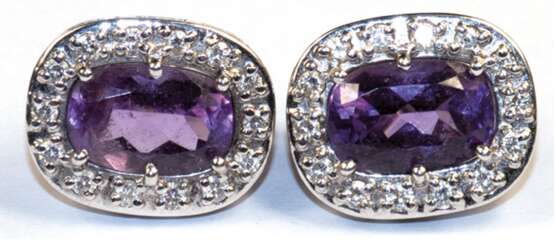 Amethyst-Brillant-Ohrstecker mit Klappbrisur, 750er WG (geprüft), je mit 1 oval facettierten Amethyst, umrandet von 14 Brillanten von zus. ca. 0,28 ct., Ges.-Gew. 8,26 g, je 1,8x1,4 cm - фото 1