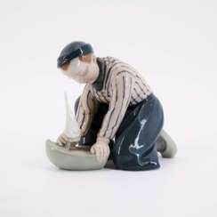 PORCELAIN FIGURINE OF A DUTCH BOY WITH SHIP