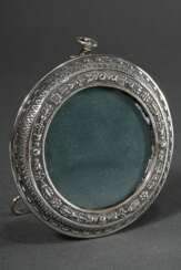 Round silver frame with embossed ornamental decora…