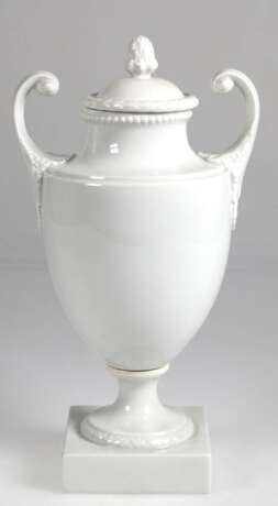 Deckelvase im Empirestil, Fürstenberg, weiß, auf quadratischem Fuß, mit 2 seitl. Handhaben, Pinienzapfen als Deckelbekrönung, H. 34 cm - фото 1 Deckelvase im Empirestil, Fürstenberg, weiß, auf quadratischem Fuß, mit 2 seitl. Handhaben, Pinienzapfen als Deckelbekrönung, H. 34 cm - фото 1