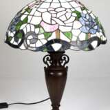 Tischlampe im Tiffanystil, 2. Hälfte 20. Jh., 1-flammig, Metallfuß in Vasenform, braun gefasst, Schirm aus farbigem Kunstglas mit Blütendekor, H. 59 cm, Dm. 40 cm - Foto 1