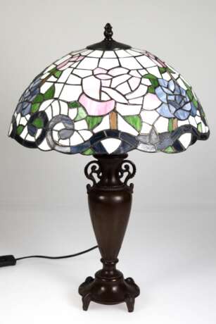 Tischlampe im Tiffanystil, 2. Hälfte 20. Jh., 1-flammig, Metallfuß in Vasenform, braun gefasst, Schirm aus farbigem Kunstglas mit Blütendekor, H. 59 cm, Dm. 40 cm - Foto 1