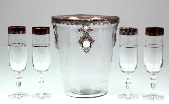 Sekt/ Weinkühler, Klarglas, reliefierter Metallrand mit 3 Abhängungen mit Steinen besetzt, H. 22 cm, Dm. 19 cm dazu 4 Sektgläser, farbloses Glas mit Goldrand (berieben) und umlaufendem Blütendekor, Rundfuß, Stiel mit ged… - Foto 1 Sekt/ Weinkühler, Klarglas, reliefierter Metallrand mit 3 Abhängungen mit Steinen besetzt, H. 22 cm, Dm. 19 cm dazu 4 Sektgläser, farbloses Glas mit Goldrand (berieben) und umlaufendem Blütendekor, Rundfuß, Stiel mit ged… - Foto 1
