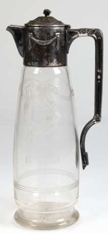 Jugendstil-Kanne mit versilberter Montur (berieben), Glaskorpus mit floralem und ornamentalem Jugendstildekor im Mattschliff, Boden mit Sternschliff, reliefierte Metallmontur mit Scharnierdeckel, Deckelbekrönung verbogen… - photo 1 Jugendstil-Kanne mit versilberter Montur (berieben), Glaskorpus mit floralem und ornamentalem Jugendstildekor im Mattschliff, Boden mit Sternschliff, reliefierte Metallmontur mit Scharnierdeckel, Deckelbekrönung verbogen… - photo 1