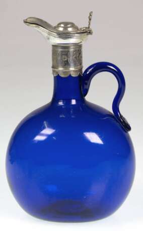 Biedermeier-Henkelkrug, blaues Glas mit Silbermontur, abgeflachter gebauchter Korpus mit ausgeschliffenem Abriß, Silbermontur mit Schnabelausguß, Scharnierdeckel und Silber-Stopfen, Ges.-H. 20,5 cm - photo 1 Biedermeier-Henkelkrug, blaues Glas mit Silbermontur, abgeflachter gebauchter Korpus mit ausgeschliffenem Abriß, Silbermontur mit Schnabelausguß, Scharnierdeckel und Silber-Stopfen, Ges.-H. 20,5 cm - photo 1