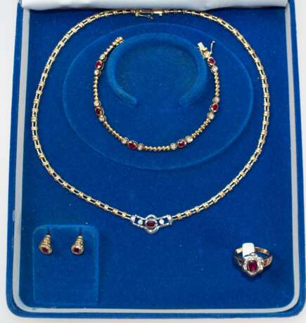 Rubin-Brillant-Schmuckset, 750er GG/WG, 5-teilig, bestehend aus Collier, Armband, Ring und Paar Ohrsteckern, Collier mit WG-Mittelteil, ausgefasst mit oval facettiertem Rubin und 2 Brillanten von zus. ca. 0,10 ct., durch… - фото 1 Rubin-Brillant-Schmuckset, 750er GG/WG, 5-teilig, bestehend aus Collier, Armband, Ring und Paar Ohrsteckern, Collier mit WG-Mittelteil, ausgefasst mit oval facettiertem Rubin und 2 Brillanten von zus. ca. 0,10 ct., durch… - фото 1