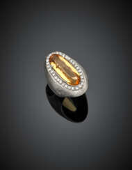 Anello in oro bianco lucido e satinato con topazio ovale di ct. 12 circa rifinito con diamanti rotondi per complessivi ct. 1