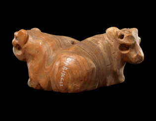 A MESOPOTAMIAN BANDED ALABASTER CONJOINED BULL AMULET