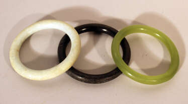 Three Asian jade bracelet in green, white and black colours, polished. 